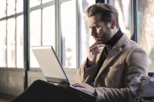 Office worker sitting at a desk looking thoughtfully at a computer screen in a modern workplace